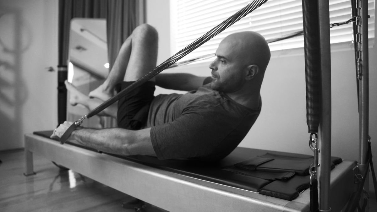 An instructor demonstrating a classical Pilates pose in a serene Los Angeles studio, embodying strength, balance, and grace.